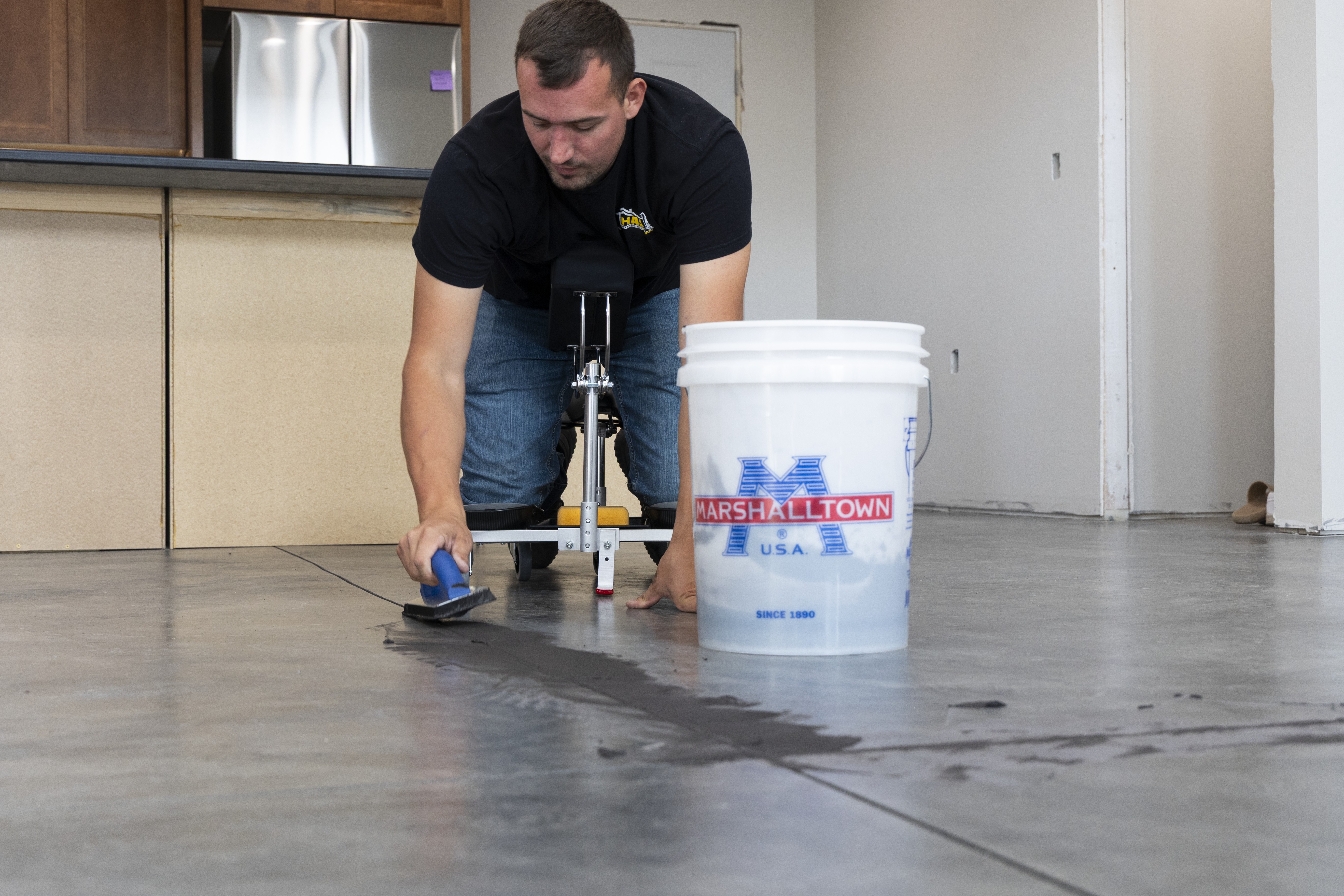 man using the RACATAC with chest support to grout concrete floors